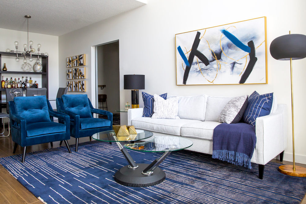 Living room with blue carpet, blue velvet chairs and a white sofa
