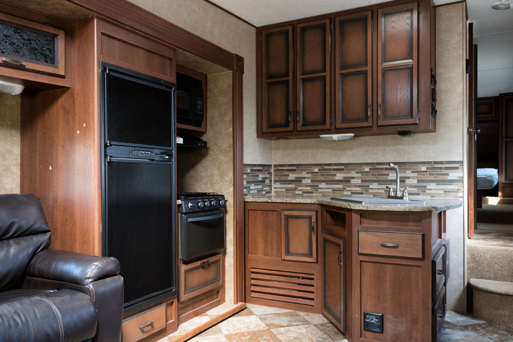 The interior of a kitchen in a renovated mobile home with plenty of cabinets and storage space