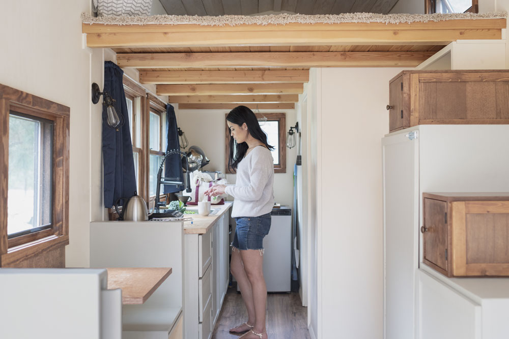 A woman standing at the kitchen sink in the narrow kitchen of her mobile home