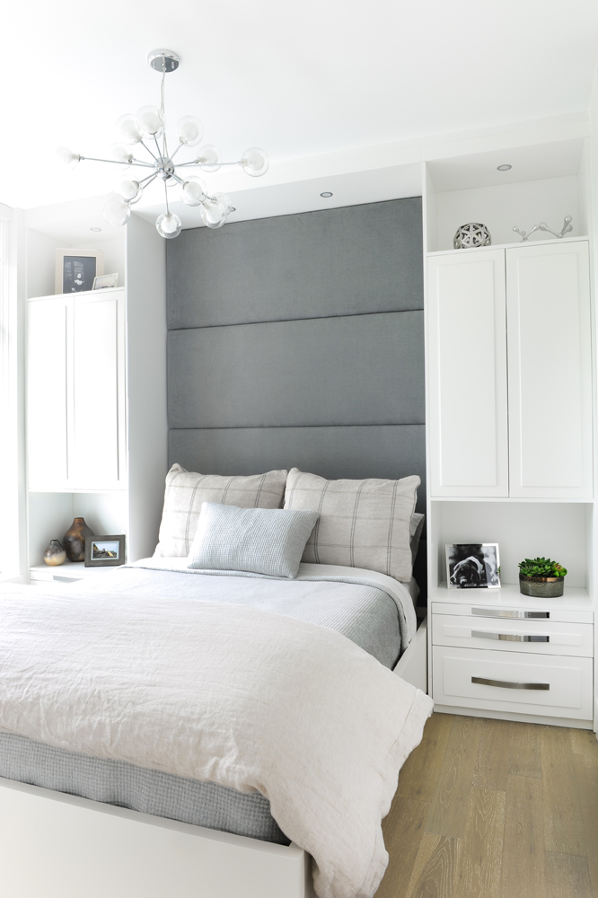Bed in front of grey panels and built-in white cupboards