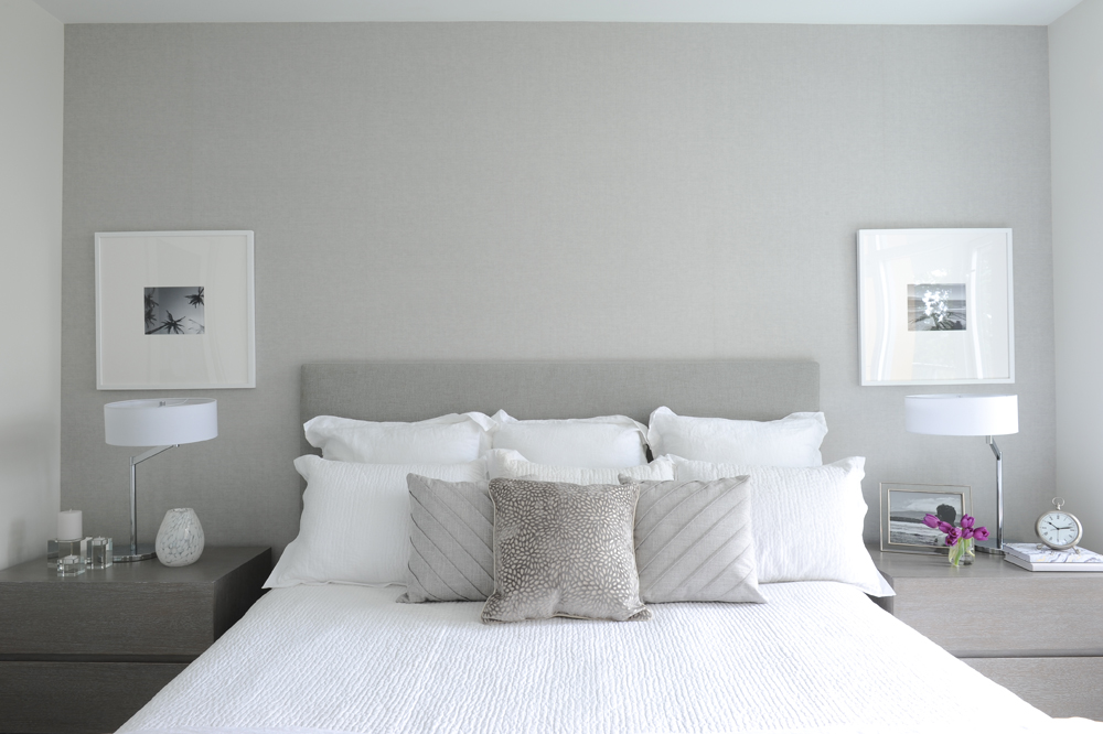 White bed with low grey headboard and grey side tables with white lamps