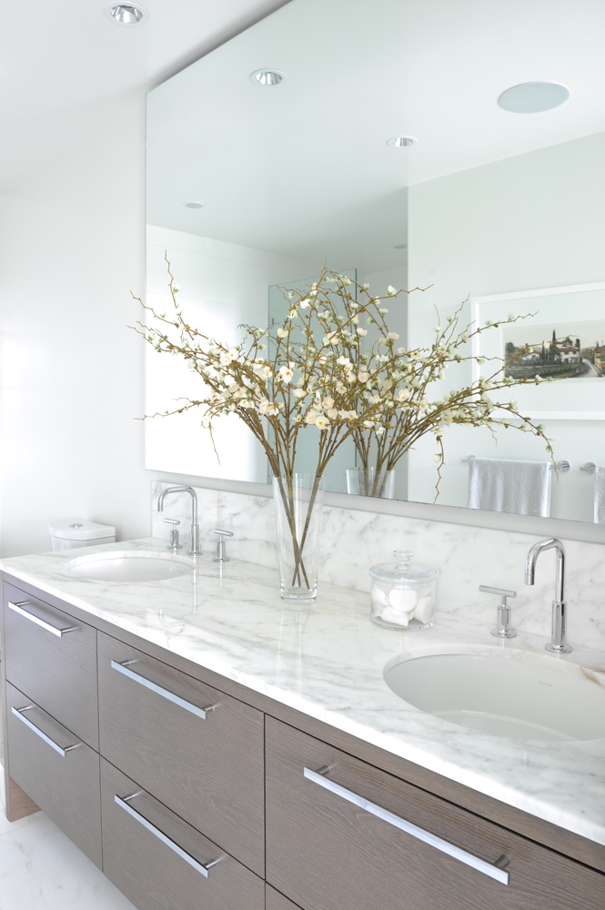 Marble topped bathroom vanity, two sinks, floral branches in vase