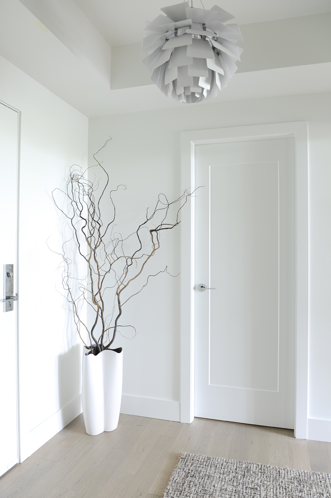 Hall with modern chandelier and curly willows in vase on floor