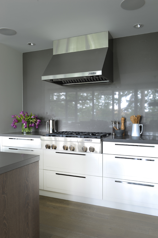 Kitchen range, grey glass backdrop, white lower cabinets, floppy purple tulips