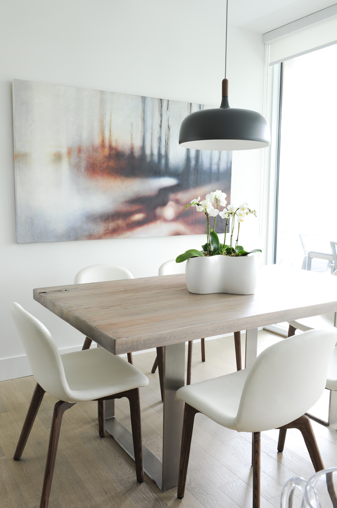 Close up of dining table, white chairs with wooden legs and blurry painting
