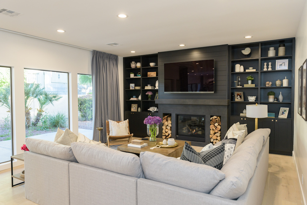 Modern grey living room with tv mounted above fireplace.