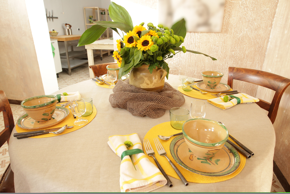 kitchen table with handmade ceramic plates and bowls and sunflowers