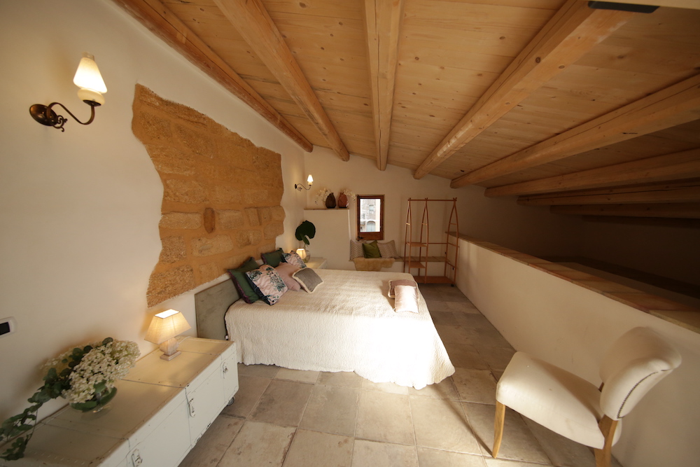 white loft bedroom with wood ceiling and natural exposed stone