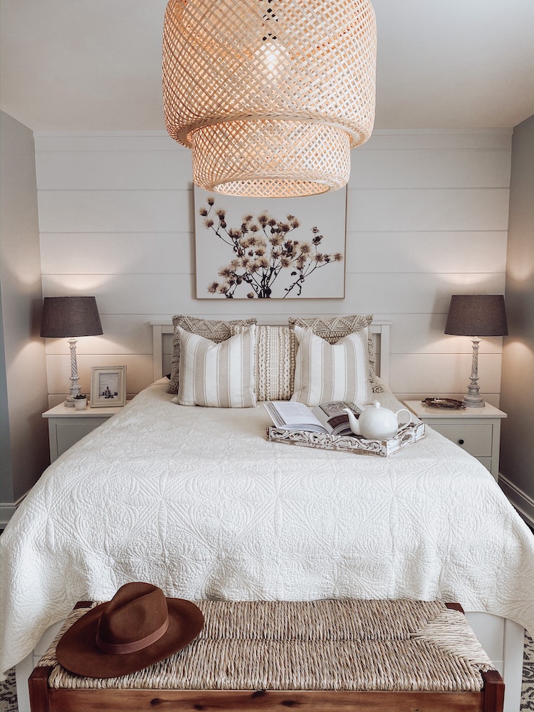 cozy white bedroom with pile of throw pillows on bed