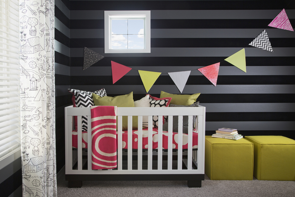 A black and brightly coloured nursery palette with patterned curtains