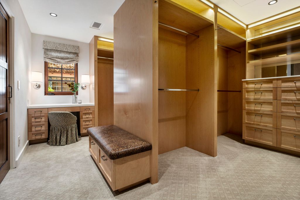 A spacious walk-in closet in the master bedroom with simple carpeting and blonde hardwood