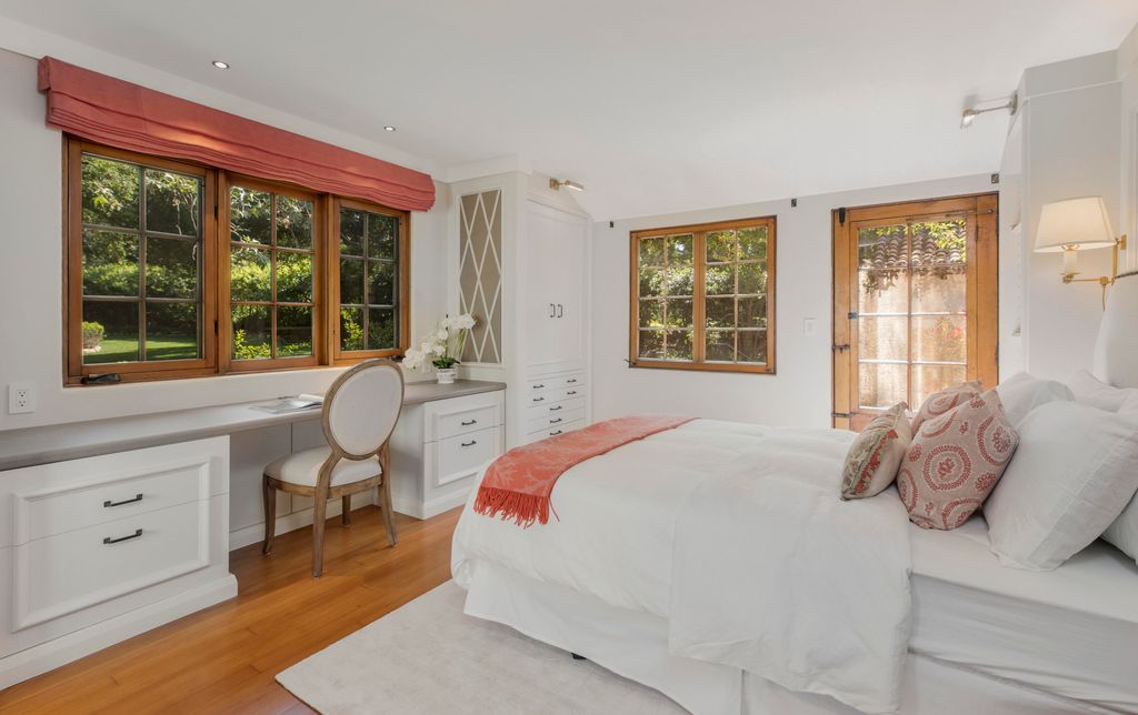 A quaint white bedroom with blonde hardwood flooring and plenty of heritage charm
