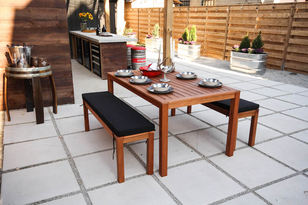 outdoor dining space with black-cushioned benches and wood table