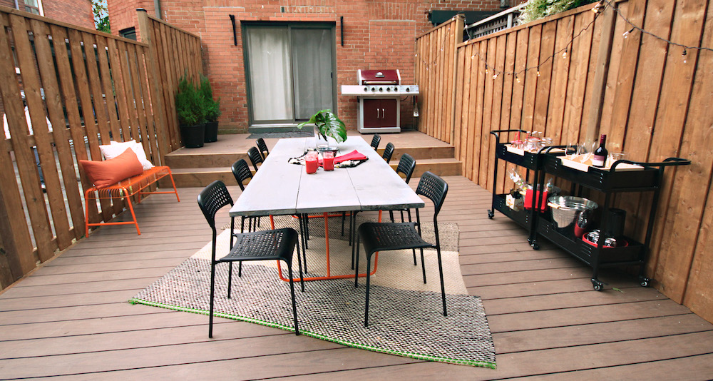 outdoor dining space with black chairs and orange bench
