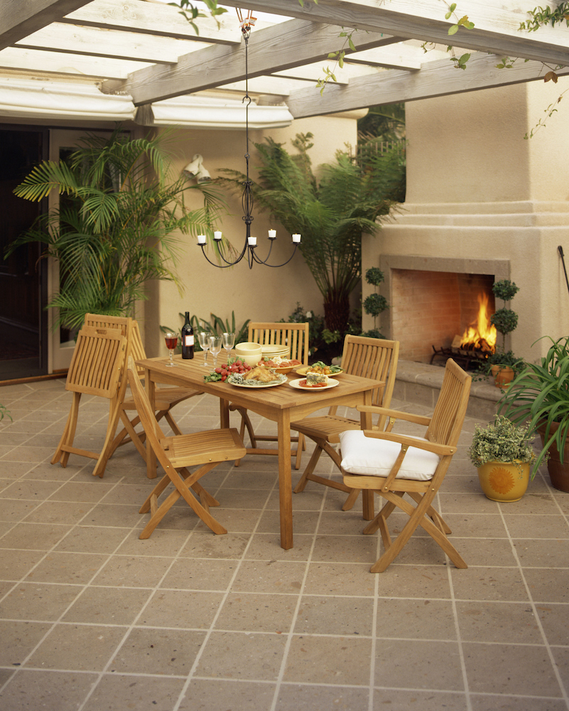 wooden dining set under pergola in garden room with fireplace