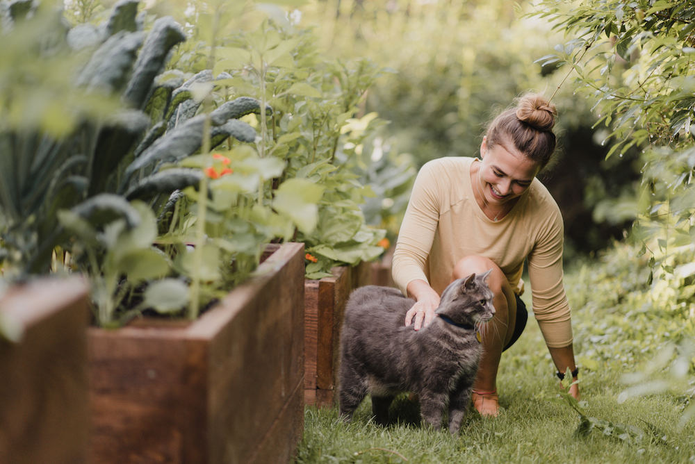 woman with grey cat in green garden