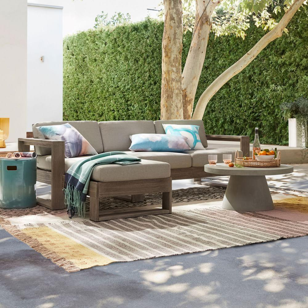 outdoor sectional on striped rug on grey outdoor patio