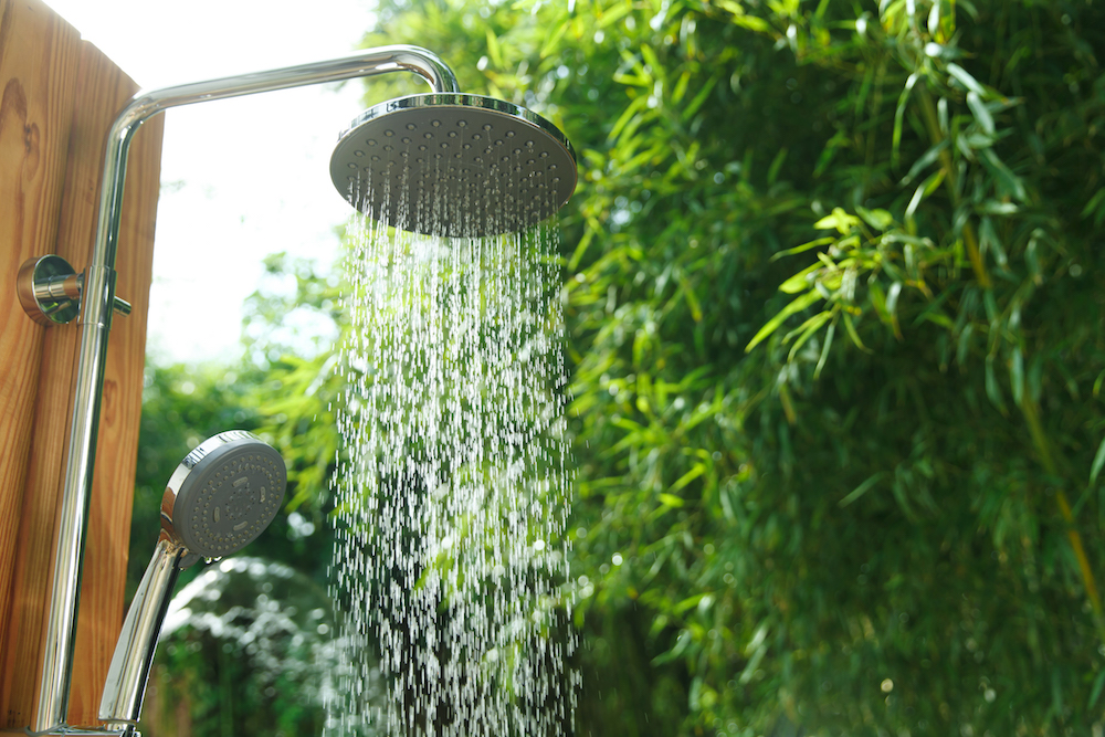 flowing outdoor shower with green trees in background