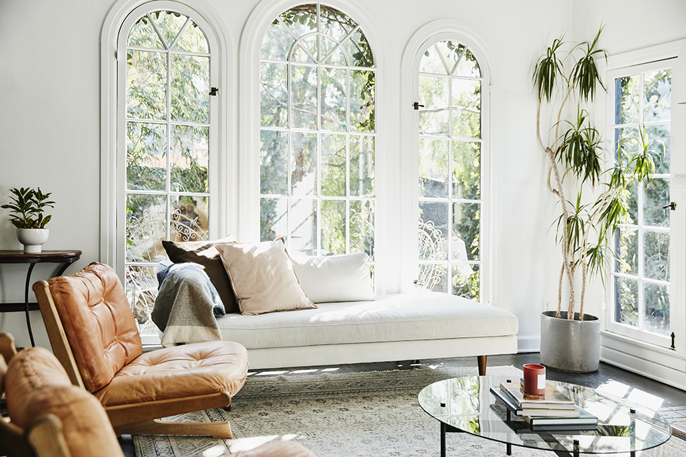 Bright living room with white couch, arched windows, and plants in the corners.