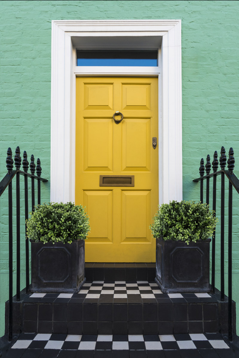 Bright yellow front door to a house with checkered stoop