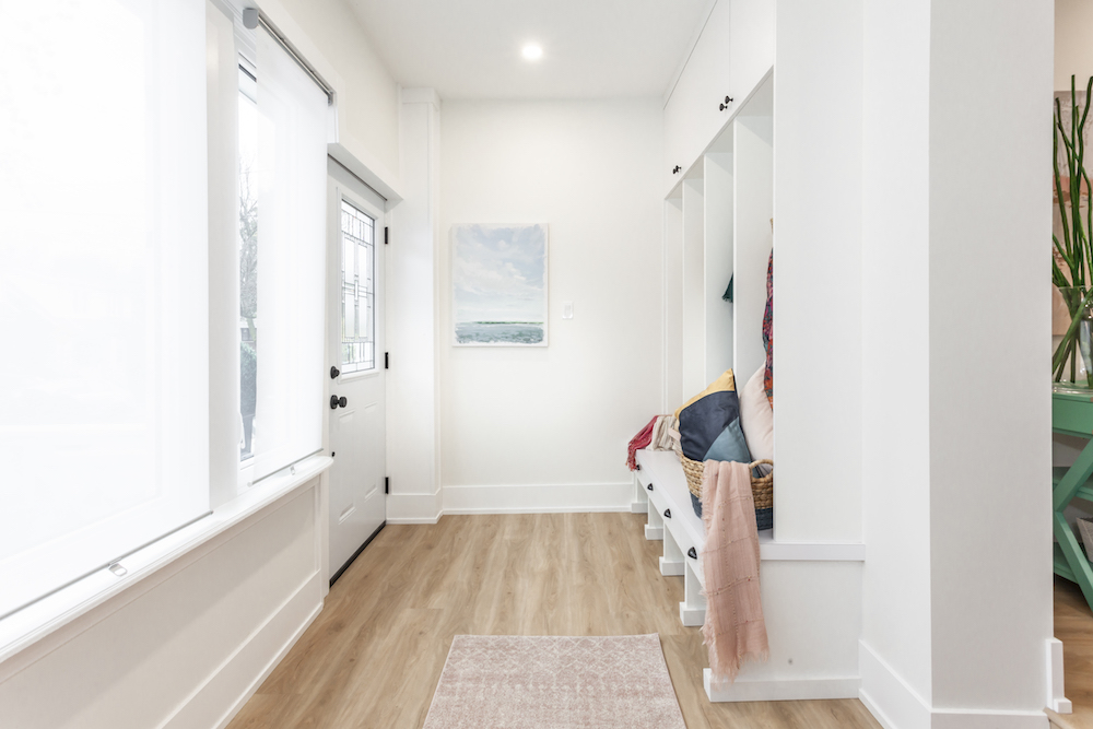 A pristine wood floor in the front entryway of a white renovated home