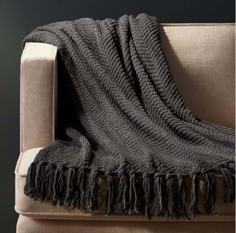 A grey throw blanket on a beige sofa