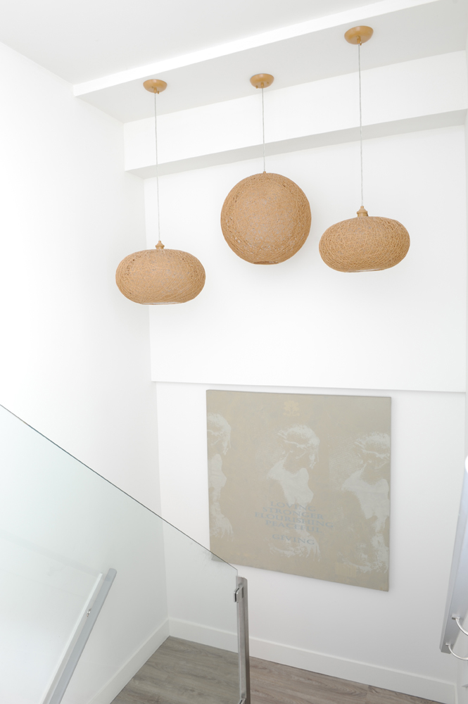 three rounded pendant lights in white stairwell