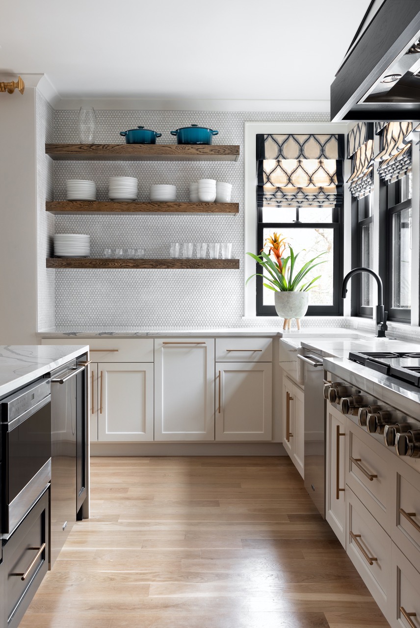 A modern farmhouse-like kitchen with floating shelves and a penny round tile backsplash