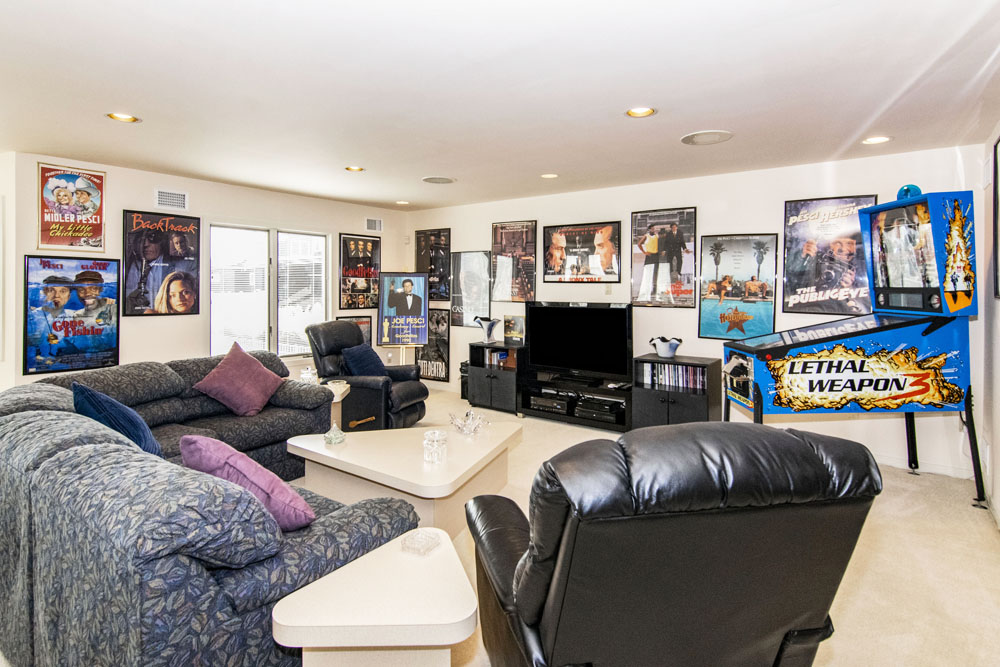A media room with a variety of film posters and a throwback pinball machine