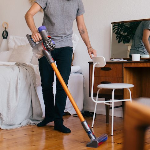 man cleaning bedroom with vacuum cleaner