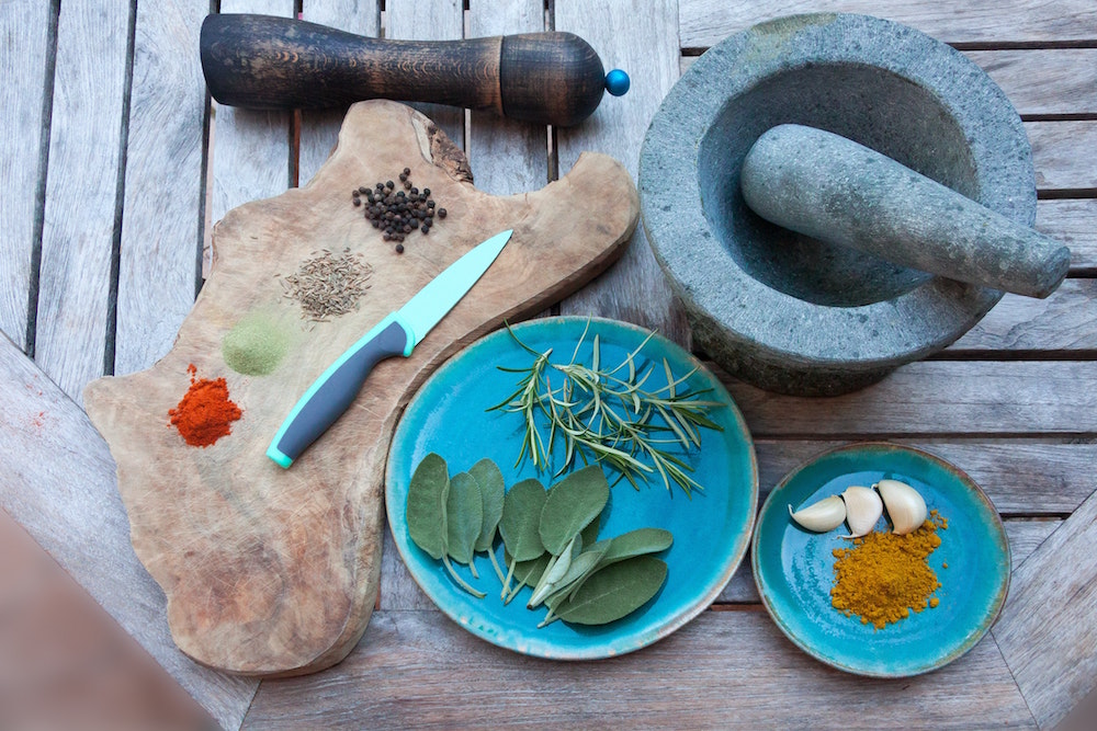 stone Molcajete, wooden cutting board and assorted spices on a wooden table