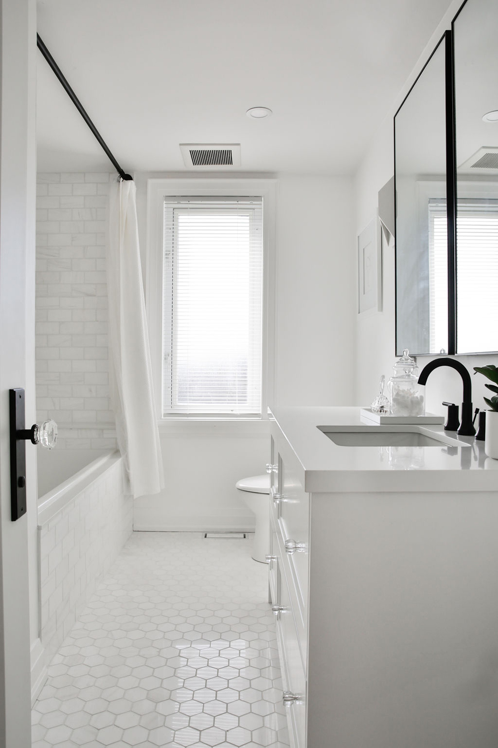 Pristine white bathroom with plenty of natural light and black faucet hardware