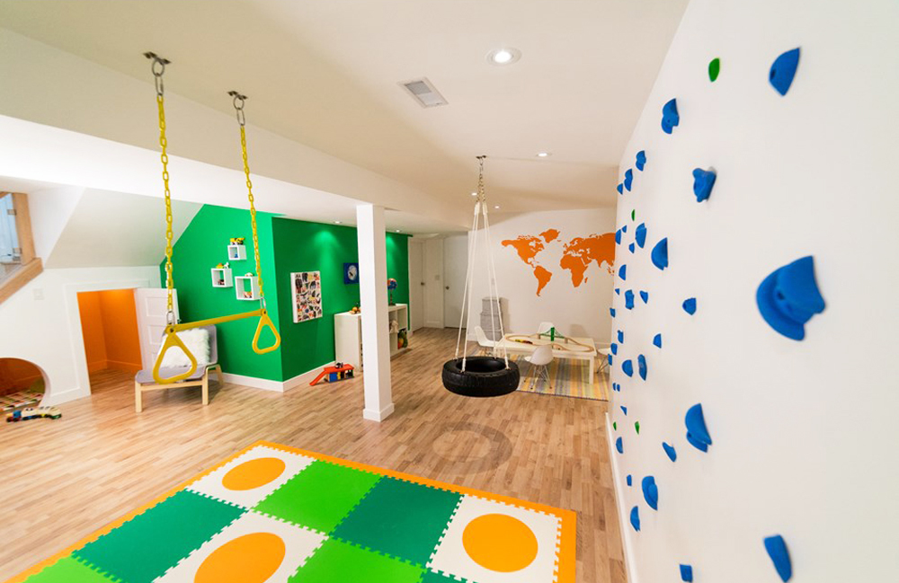 A kids' playroom in a renovated basement, complete with rock climbing walls and a tire swing