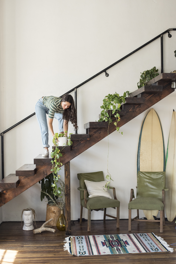Woman arranging plants on wooden staircase