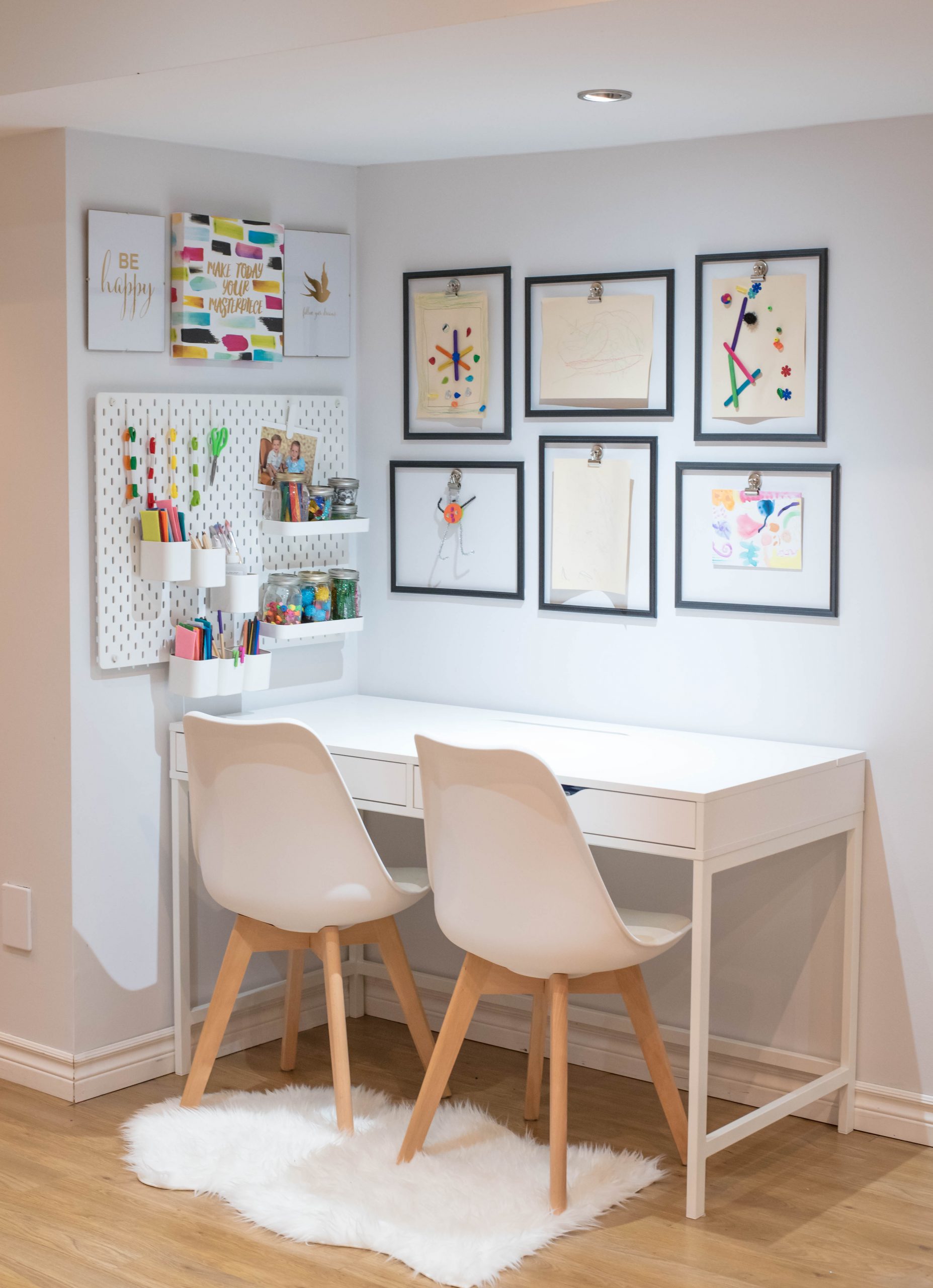 Kids' desk with artwork above it and two chairs