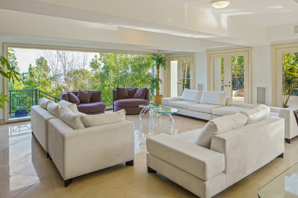 A spacious living room with plenty of seating space and French doors that open onto a shaded patio