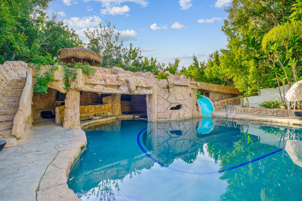 A luxurious, spa-like swimming pool with a slide and waterfall