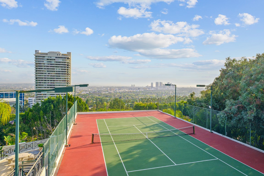 A rooftop enclosed tennis court with views overlooking the city of Los Angeles
