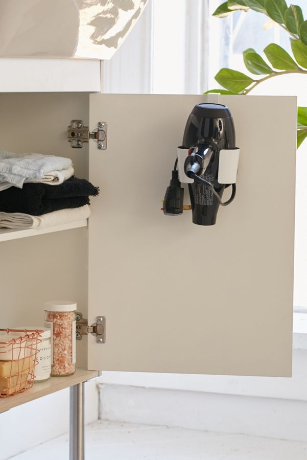 black hair dryer hanging inside beige bathroom cabinet