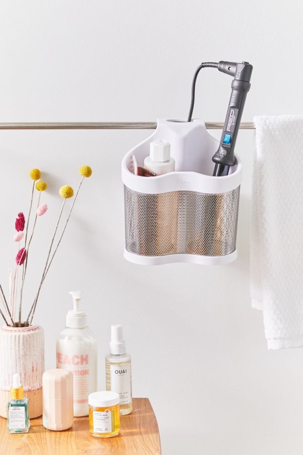 curling iron and hair products in white hanging shelf in bathroom