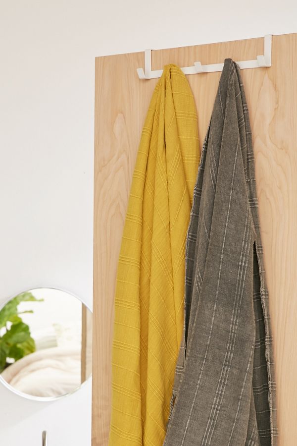 white hook on wood door frame with yellow and plaid hanging blankets