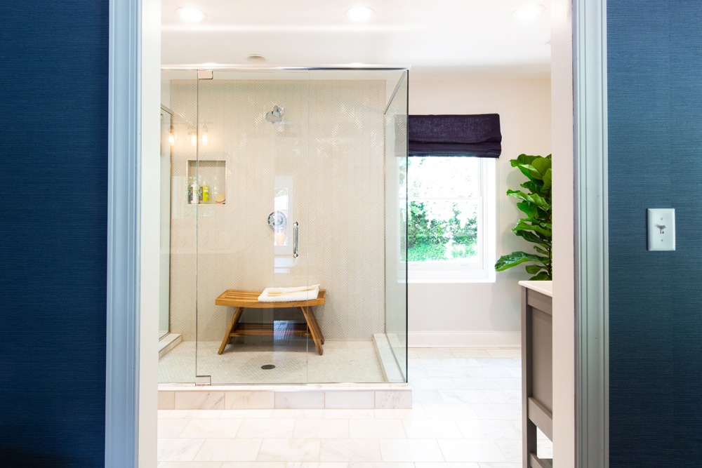 A standing shower with glass walls and a custom wood bench with exposed pipes