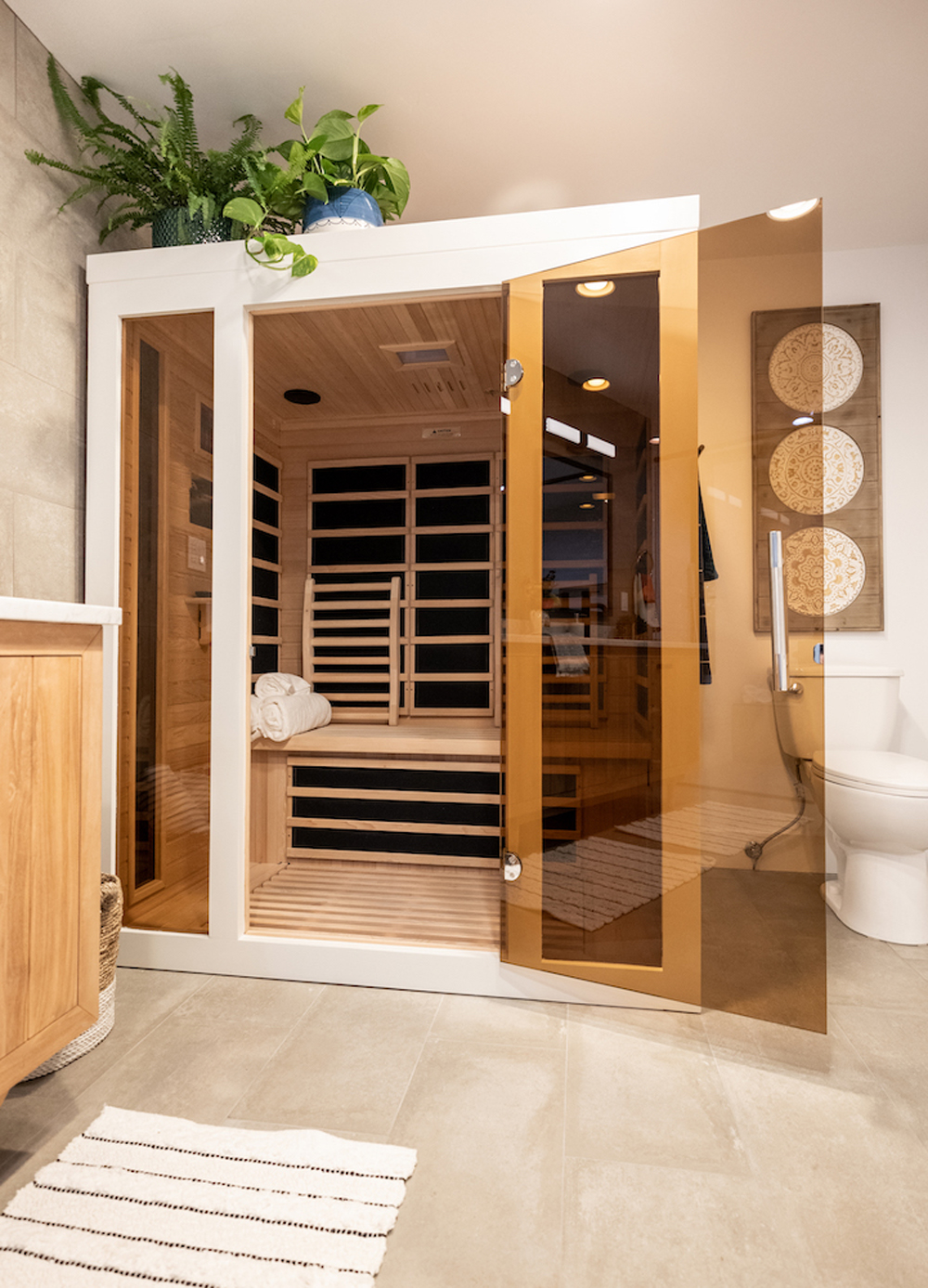 A renovated master bathroom with a large, private cedar-lined infrared sauna with a tinted glass door