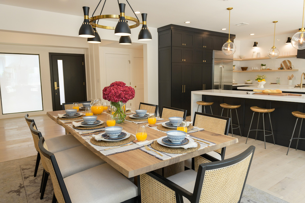 A large, sleek dining room with wicker-backed chairs and modern chandelier