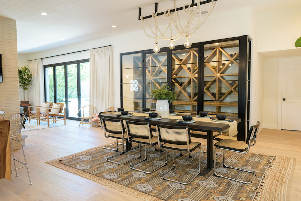 An open-concept dining room with with pops of bold blacks, a rope chandelier and a jaw-dropping temperature-controlled wine rack