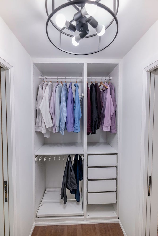 white walk-in closet with shirts and pants hanging