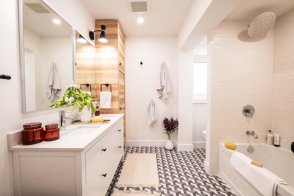 A renovated bathroom with custom wood lockers, glossy oversized brick-inspired shower tile and on-trend flooring