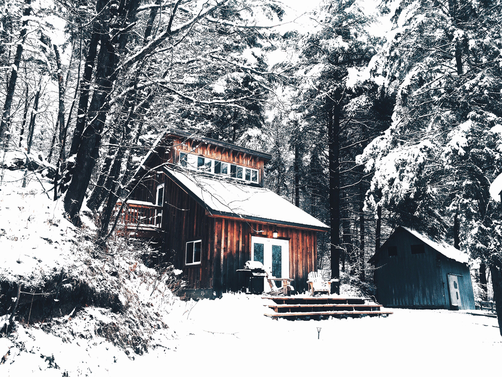 A cottage-type home in a snowy, forrested area in winter