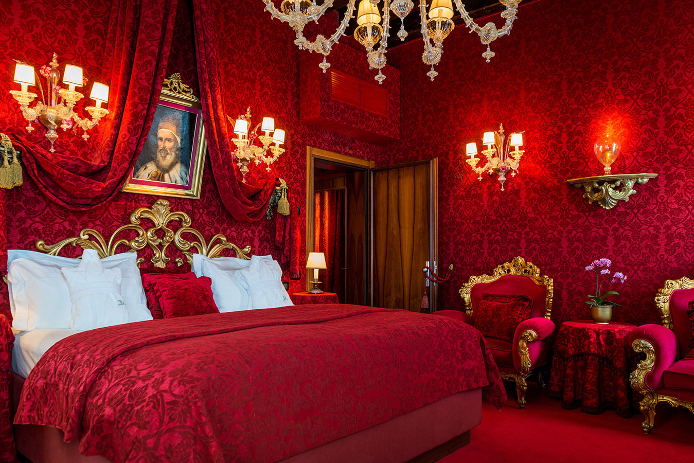 lush red and gold bedroom with chandelier and sconces