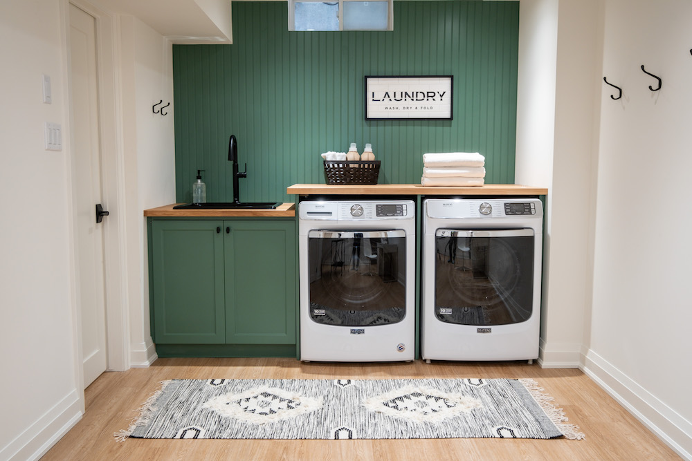 laundry room with light wood floors and green cabinets and wall